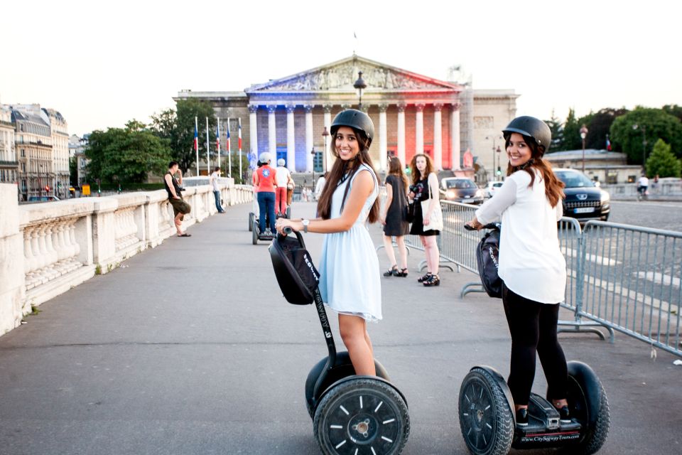 A photo of a smiling couple riding Segways and enjoying the sights of Paris.